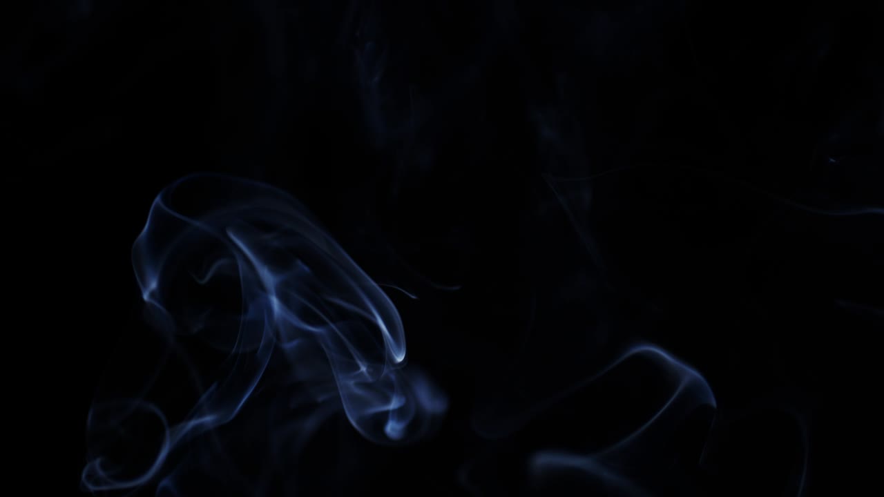 fumo che galleggia lentamente nello spazio contro uno sfondo nero.