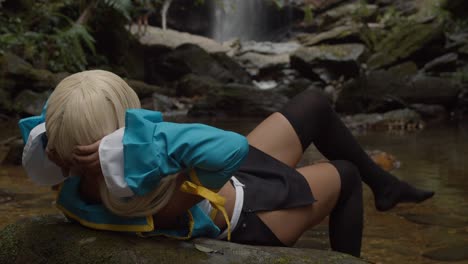 Sexy-Cosplayer-De-Anime-Recostada-Sobre-Una-Roca-Con-Una-Increíble-Cascada-En-El-Fondo