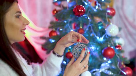 happy girl decorating christmas tree with balls. lots of gift under the tree. children decorating a christmas tree