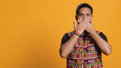 man covering eyes, ears and mouth with hands, studio background