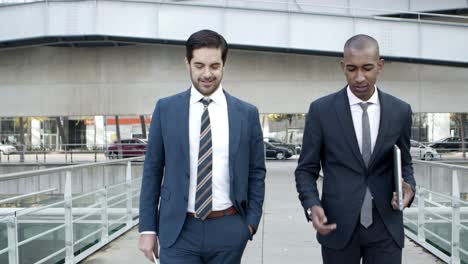 professional businessmen walking and talking on street