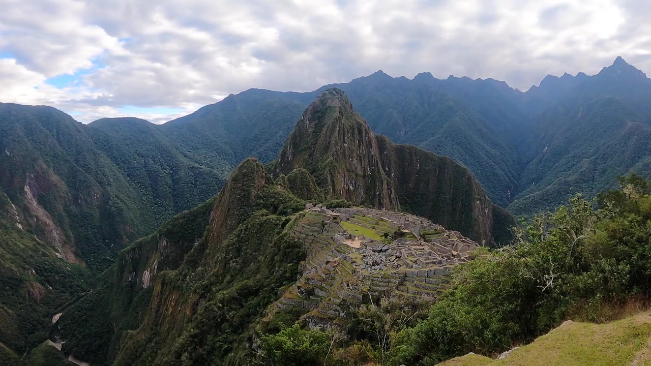 Turisti che fanno escursioni con vista sull'antica cittadella Inca e sulle montagne circostanti delle Ande