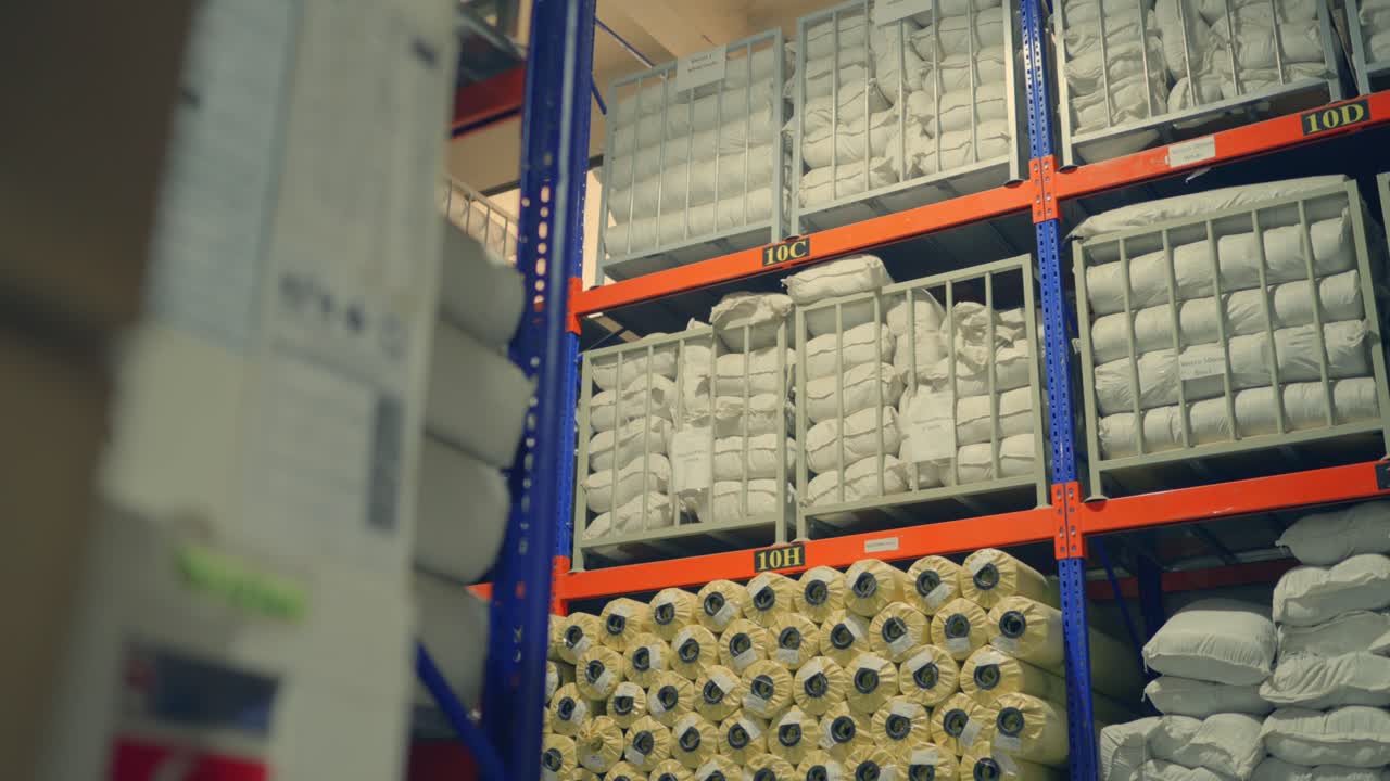 Scaffalature di magazzino che stoccano rotoli di tessuto all'interno di una grande fabbrica industriale in Pakistan