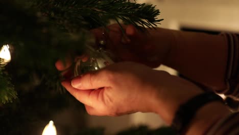 Weibliche-Hände-Hängen-Eine-Glänzende-Kugel-An-Den-Weihnachtsbaum---Nahaufnahme