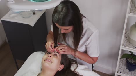 Caucasian-woman-wearing-face-mask-lying-down-having-eyebrows-dyed