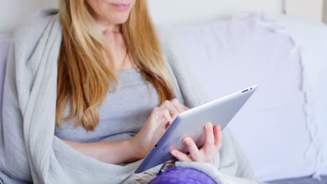 Woman-wrapped-in-blanket-using-digital-tablet-in-living-room-4k