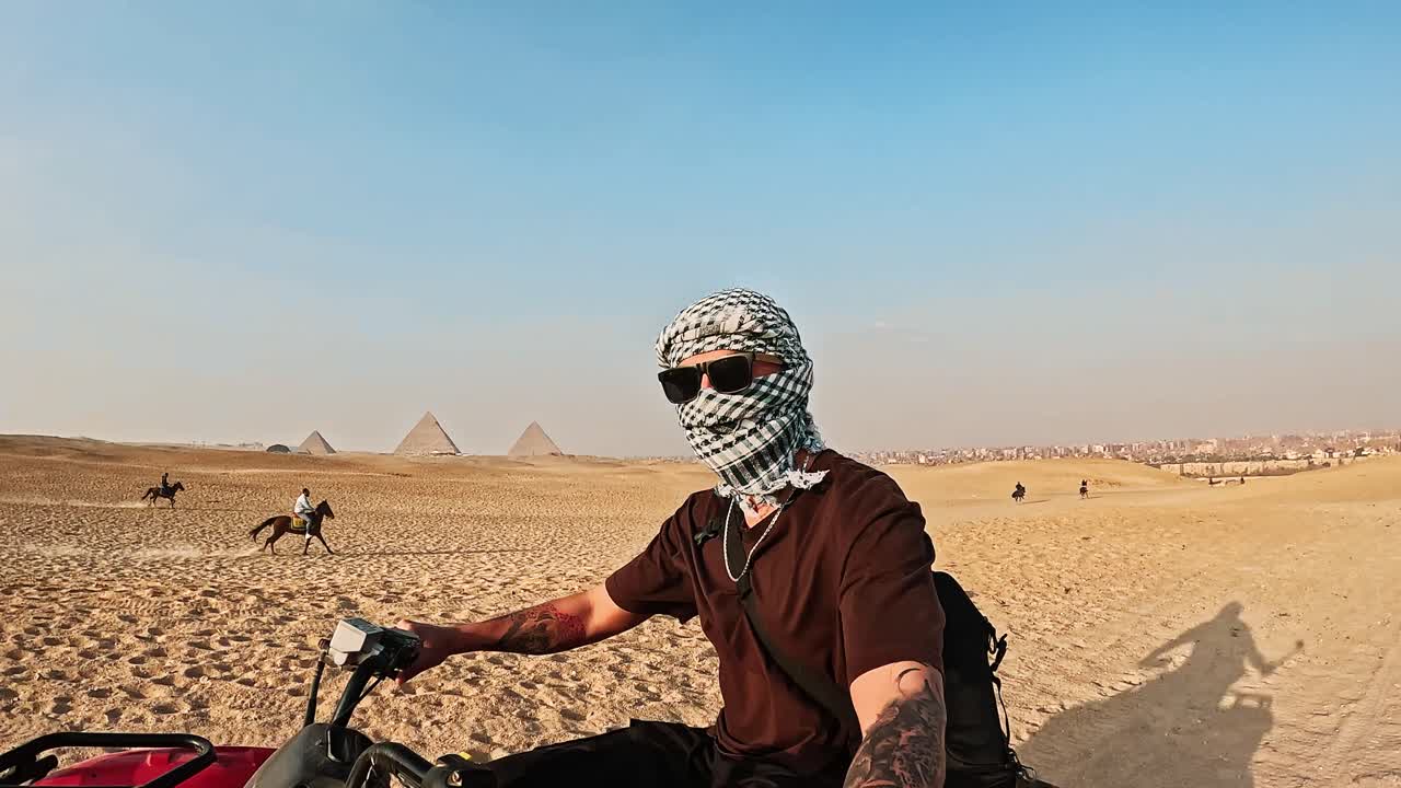 Uomo in quad nel deserto con le Piramidi di Giza sullo sfondo