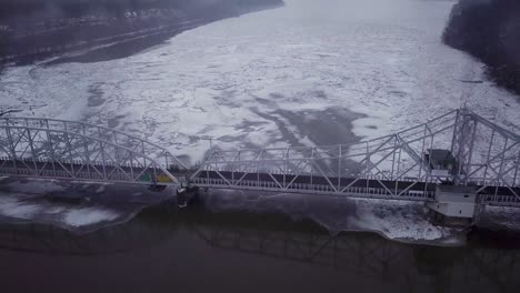 Drone-flying-high-over-swing-bridge-with-big-ice-chunks-on-a-snowy-river-in-Connecticut-during-a-winter-storm