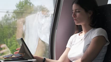 Hermosa-Mujer-Pasajera-Leyendo-Un-Libro-Electrónico-En-Un-Viaje-En-Tren,-Serena-Y-Pensativa