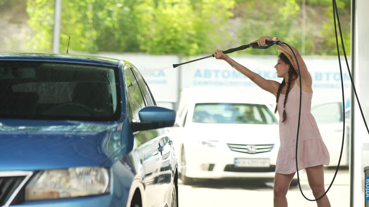 mujer lavando un coche en un lavado de coches de autoservicio