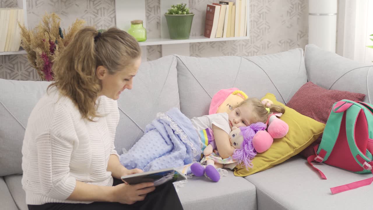 la madre le está leyendo un cuento de hadas a su hija y la niña se está preparando para ir a la cama.