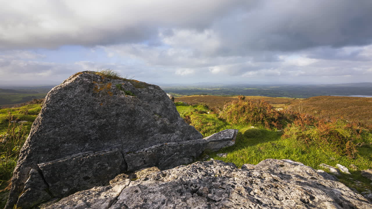 lapso de tiempo del paisaje natural rural con ruinas de bloques prehistóricos de piedra sepulcral en primer plano durante el día nublado soleado visto desde carrowkeel en el condado de sligo en irlanda