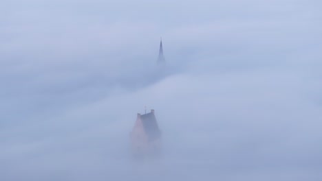 Churches-at-Bolsward-rising-above-the-clouds-during-sunrise,-aerial