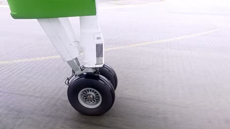 closeup airplane wheels turn slowly, accelerating on airport asphalt with painted markings