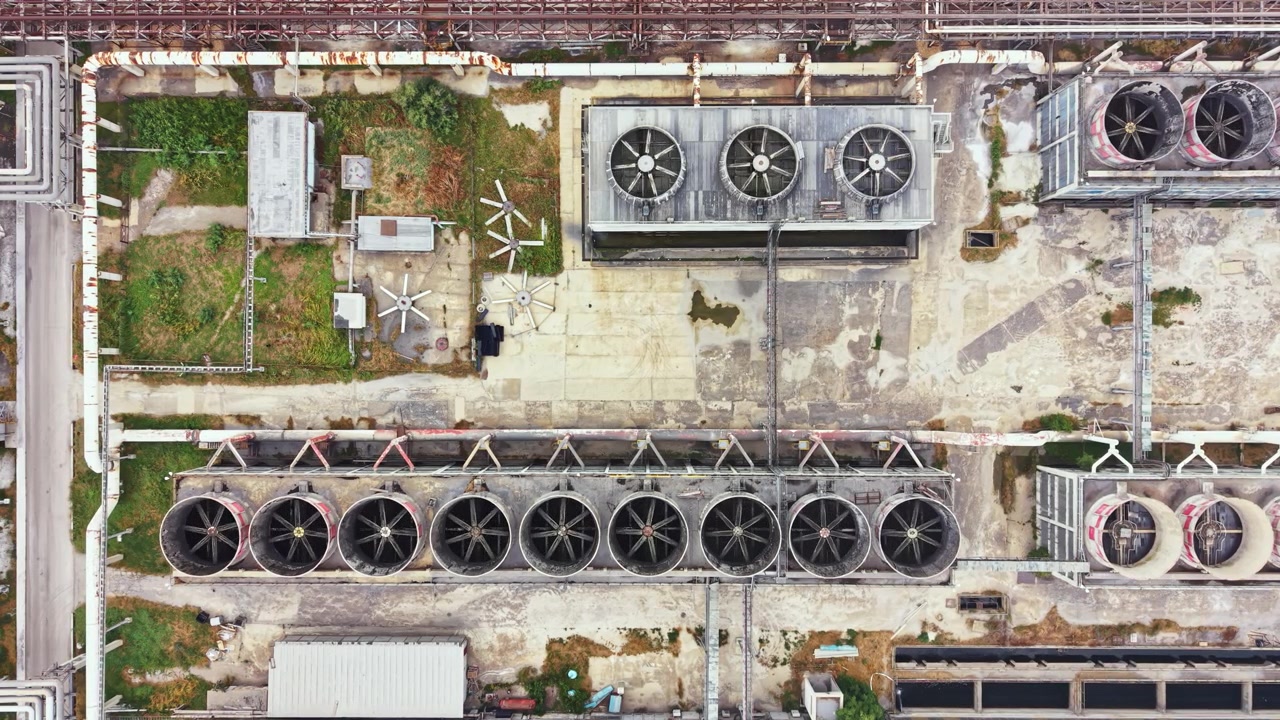 Industrial cooling system seen from above with large fans and green areas in an urban setting