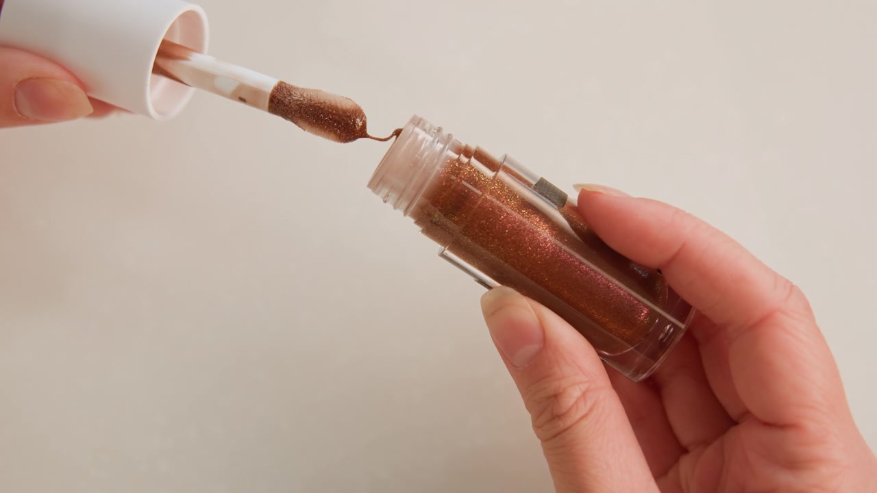 Vista ravvicinata delle mani che trasferiscono una spezia marrone grossolana da un piccolo barattolo di vetro trasparente in un coperchio di plastica bianco, mostrando un movimento controllato di versamento, prelievo e misurazione con granuli visibili e un'azione semplice