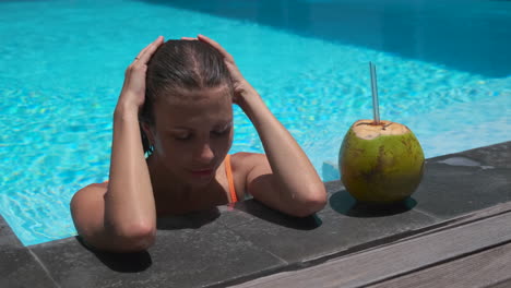 mujer relajándose en una piscina con bebida de coco