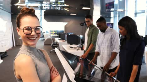 Female-executive-sanding-with-arms-crossed-while-colleagues-working-in-office-4k