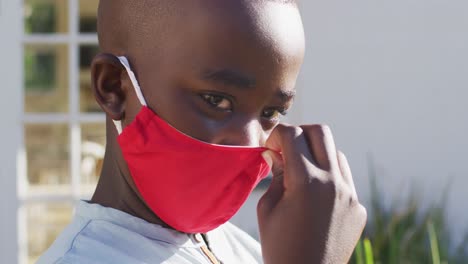 portrait of african american boy wearing face mask outdoors on a bright sunny day