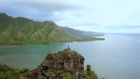 Disparo-De-Un-Dron-Que-Rodea-A-Un-Par-De-Excursionistas-Parados-En-La-Cima-De-Los-Acantilados-En-La-Caminata-Del-León-Agachado-En-Oahu,-Hawaii