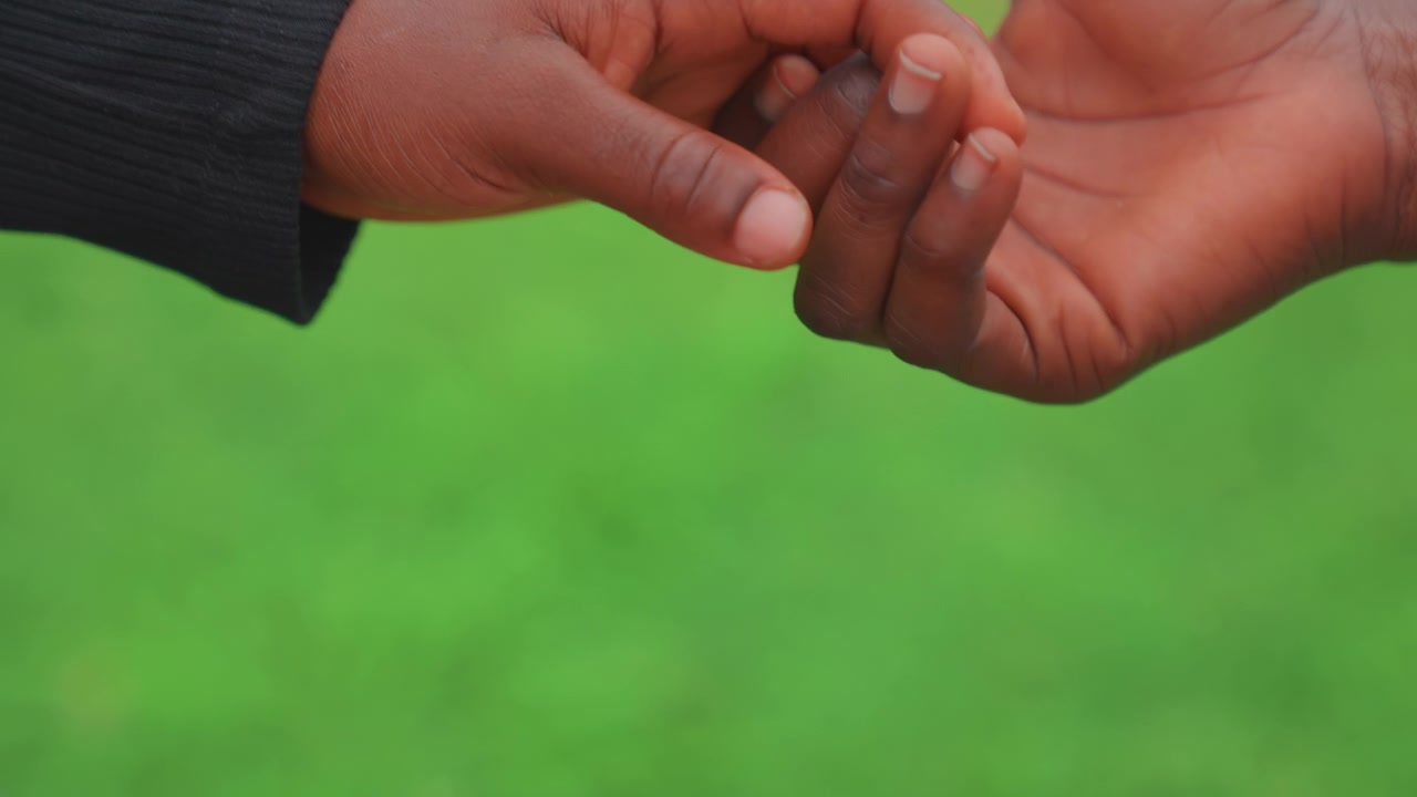 Black mother and child fingers releasing in trust exercise, gentle fingertip touch transitions to open palm, soft bokeh grass background and tender moment showing bond and security