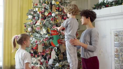 Liebevolle-Mutter-Und-Ihre-Kinder-Schmücken-Gemeinsam-Den-Weihnachtsbaum-In-Einem-Gemütlichen-Wohnzimmer