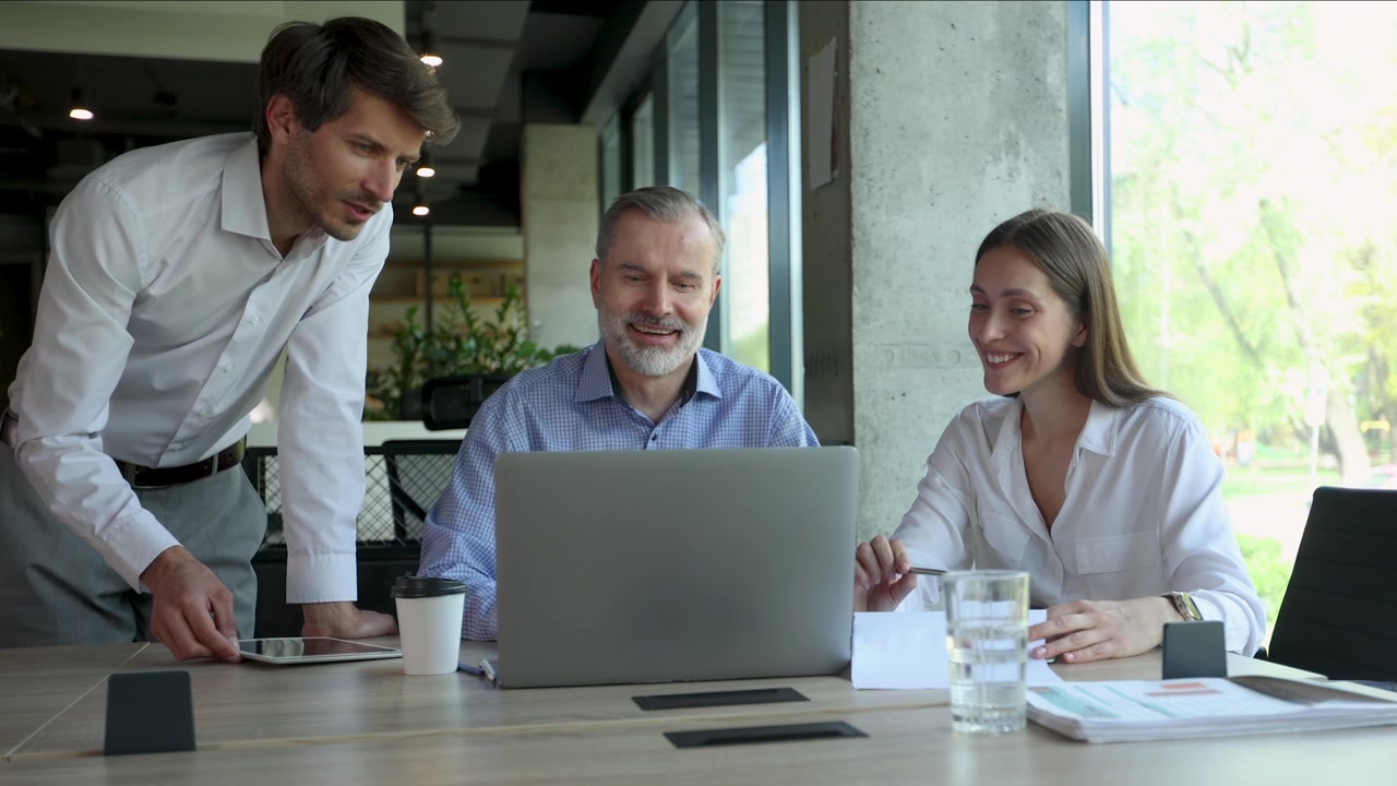 Tre colleghi d'affari che collaborano al laptop in un ufficio moderno