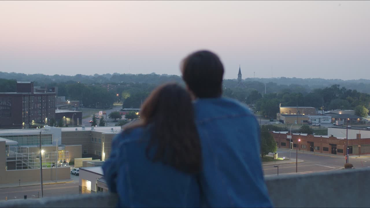 Man and woman look at cityscape from a tall building in an urban area