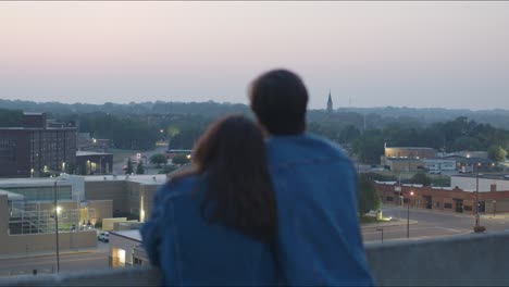 man and woman look at cityscape from a tall building in an urban area