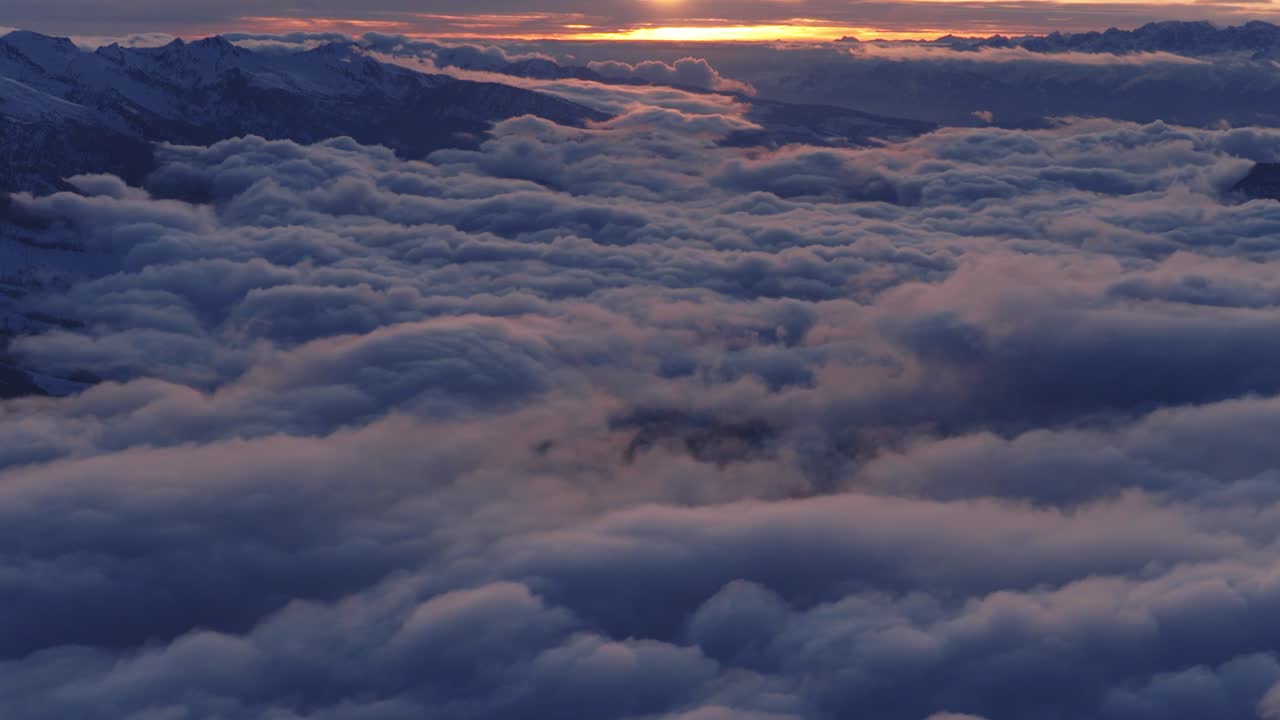 Un mare di nuvole ondeggianti si estende verso l'orizzonte luminoso al tramonto sopra le montagne della Catena del Lagorai, in Val di Fiemme, Trentino, Italia - Ripresa aerea con drone