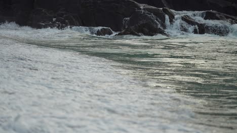 un primer plano de las olas derramándose en la playa de arena