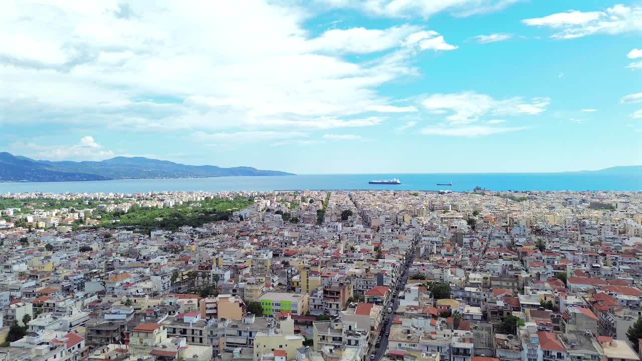 Aerial push in footage , view to Messinian gulf, flying over cityscape of Kalamata, blue sky with white clouds, on a spring day 4K