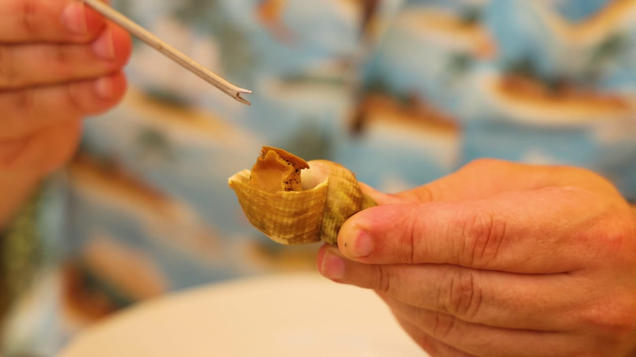 manos extrayendo almejas de las conchas con una herramienta