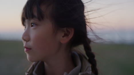 close-up-portrait-little-asian-girl-smiling-happy-looking-around-enjoying-summer-vacation-on-seaside-park-sunset-real-people-series