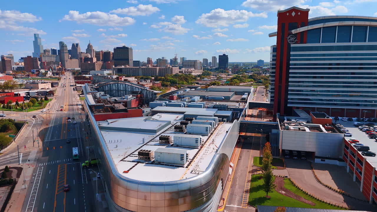Detroit, USA, 28 juli 2025: Närmar sig taket på det moderna Motor City Casino i Detroit, Michigan, USA. Silhuett av stadens centrum mot blå himmel med små moln i bakgrunden