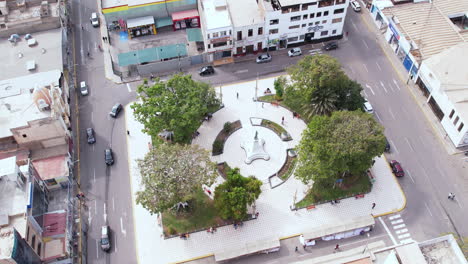 amazing and great general drone shot over the famous park "plazuela de elías aguirre" in the city of chiclayo, peru during a cloudy day while cars pass by