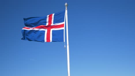 Static-closeup-shot-of-Iceland-national-flag-in-strong-wind-against-clear-blue-sky-on-a-sunny-day
