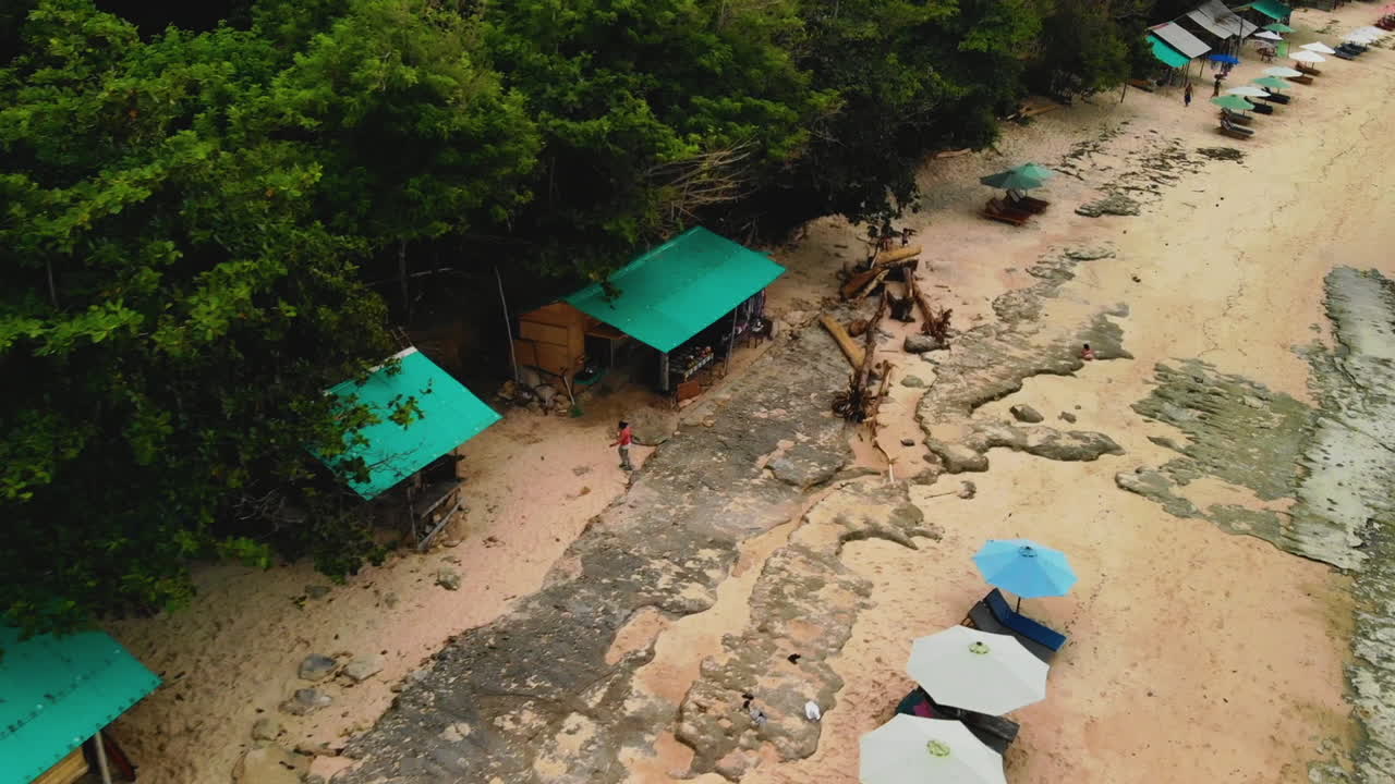 volando sobre una hermosa playa de arena blanca donde tanto los lugareños como los turistas se divierten