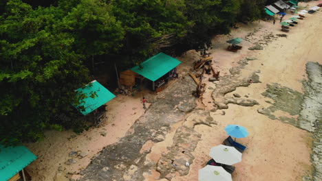 Sobrevolando-Una-Hermosa-Playa-De-Arena-Blanca-Donde-Tanto-Locales-Como-Turistas-Se-Divierten