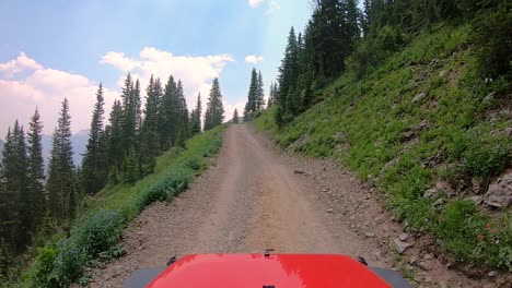 pov over the hood of vehicle on narrow off road trail trail cut into the mountain side