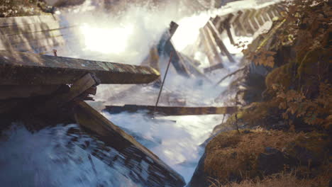 Rápidos-De-Agua-Que-Fluyen-Por-Un-Tobogán-De-Troncos-Y-Se-Estrellan-Contra-Vigas-De-Madera-Dañadas-Con-Rocas-Cubiertas-De-Musgo-Durante-El-Otoño-4k-Prores