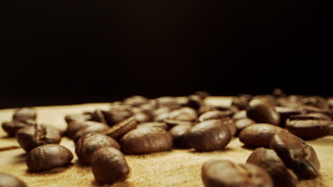 Close-camera-movement-through-fresh-coffee-beans-laying-on-a-wooden-surface