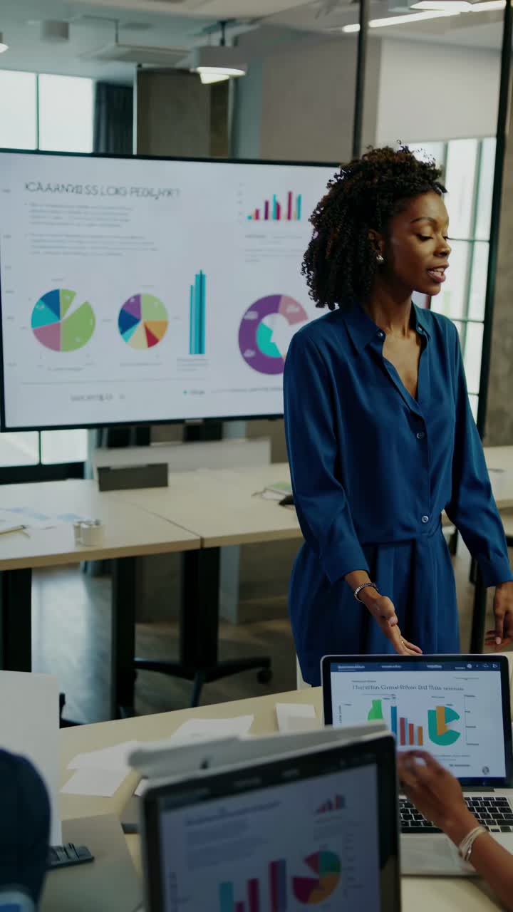A professional video still of a businesswoman presenting data on a screen