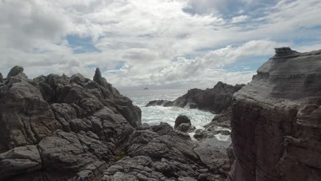 Slow-motion-waves-breaking-onto-rocks-on-bright-and-sunny-day