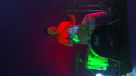 video luz de neón brillante vertical un baterista masculino toca en un estudio con luz de neó y humo