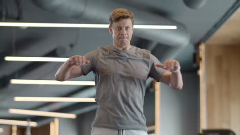 hombre de fitness serio calentando en el gimnasio. hombre fuerte haciendo ejercicios en el club deportivo