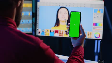 Fotograf-Folgt-Einem-Online-Tutorial-Auf-Einem-Greenscreen-Telefon-über-Die-Verwendung-Von-Fotobearbeitungssoftware