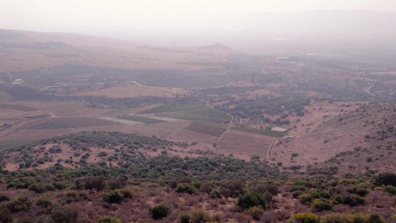 Vista aerea di un versante collinare boscoso che rivela una vasta valle agricola