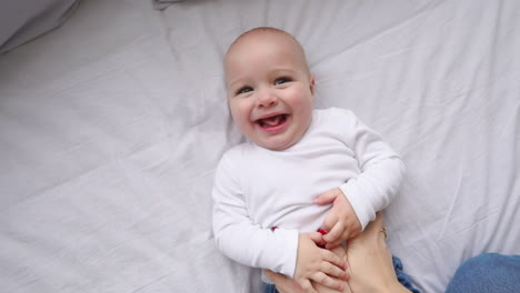 a newborn baby lying on the bed, looking into the camera and around on a white bed sheet, view from above. infant knows the world, top view