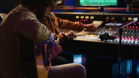 creative musician singing guitar in professional studio control room